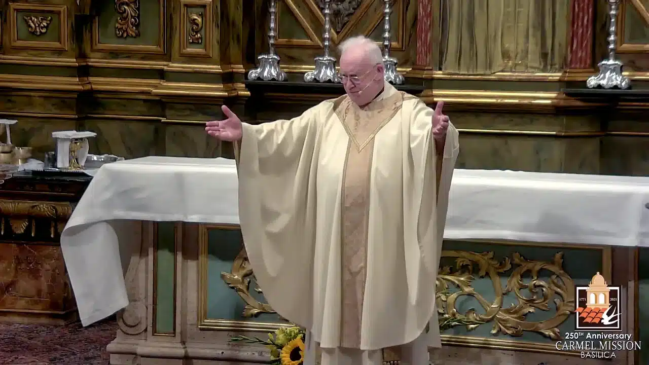 priest in white robe with hands raised and head down